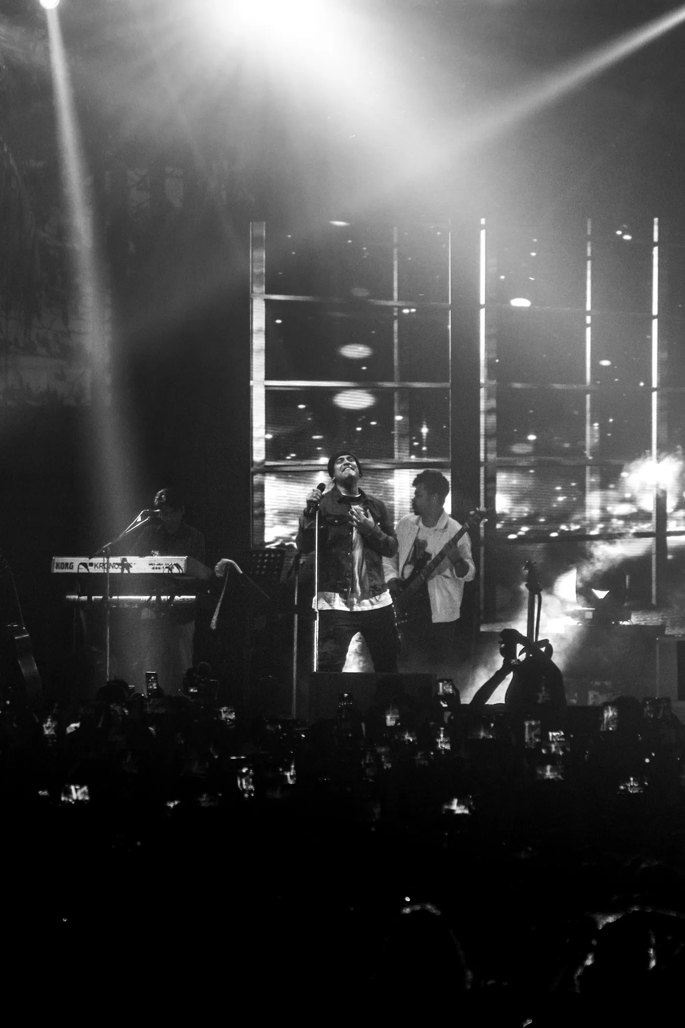 Singer on stage in black and white, light beams overhead